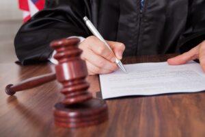 Close-up of a male judge writing on a document in a courtroom.