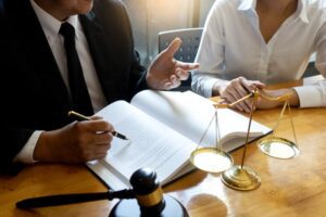 Lawyer discussing arbitration agreement with client, gavel and scales of justice in view.
