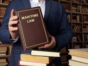 A jurist holds a book on maritime law, also known as admiralty law, which encompasses a collection of laws and conventions governing maritime activities.