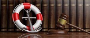 Banner concept for the law of the sea, featuring a lifebuoy, a navy ship anchor, and a judge's gavel against a backdrop of law books in a lawyer's office.