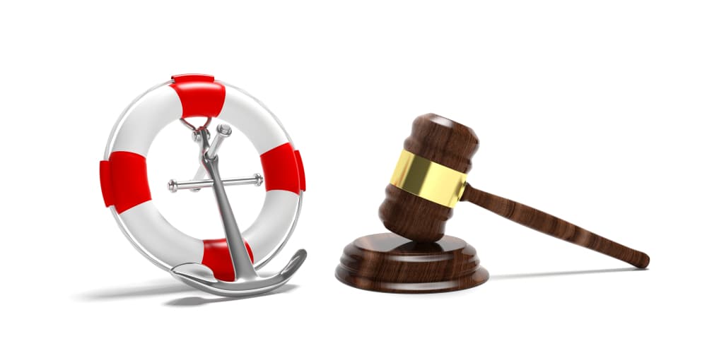 The idea of maritime law. A lifebuoy, a naval ship anchor, and a judge's gavel depicted against a white background.