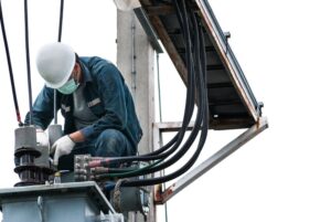 Electrician engineer performing maintenance on a high voltage pole, isolated on a white background.