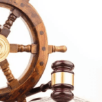 a gavel laying on top of money beside a ship's wheel.