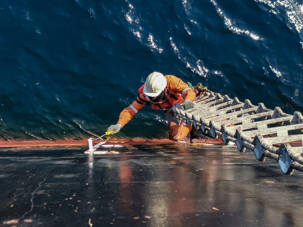 A ship crew is painting draft mark or load line of a cargo ship or bulk carrier