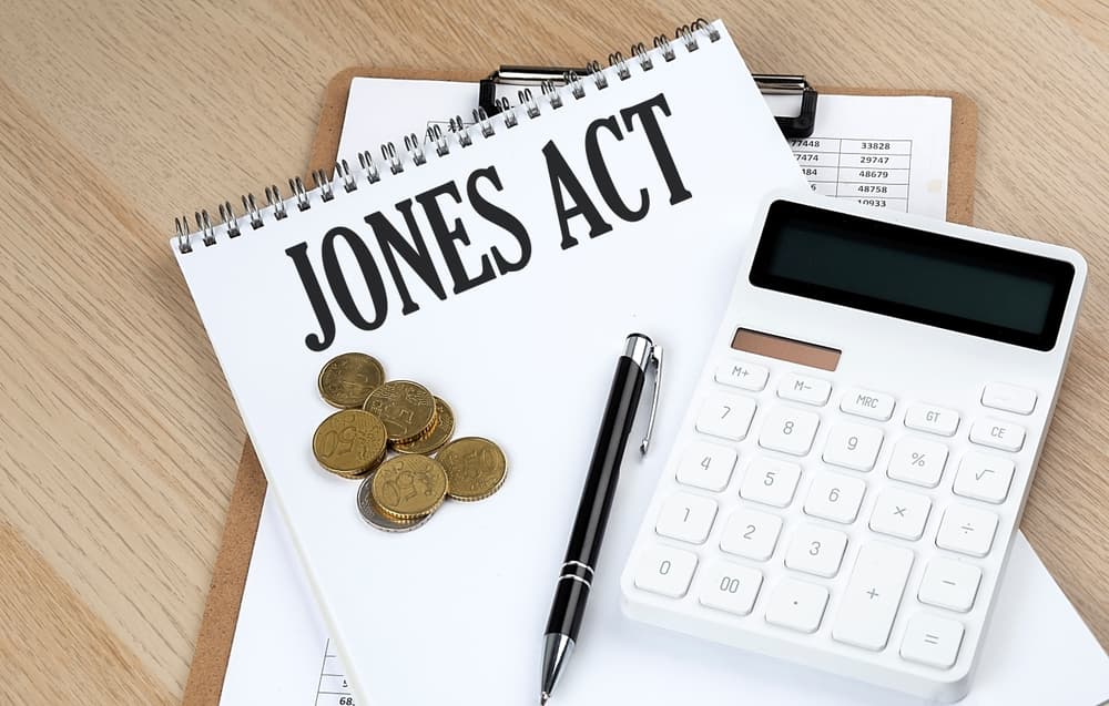 Text related to the Jones Act is displayed alongside a chart, a calculator, and a collection of coins, symbolizing business and financial calculations.