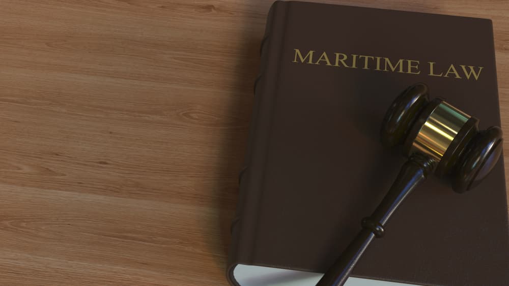3D rendering of a court gavel resting on a book titled "Maritime Law." Conceptual design illustrating the intersection of law and maritime issues.